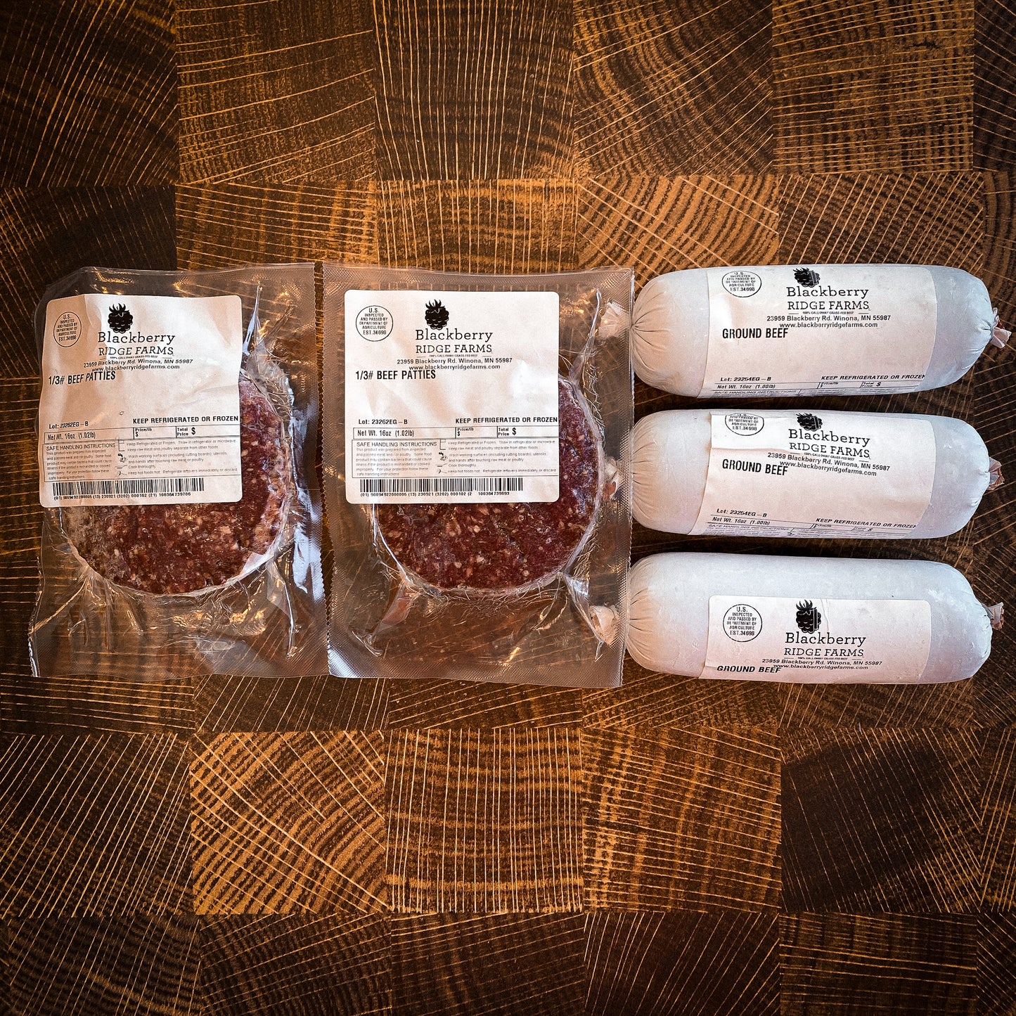 The contents of the All Natural Bluff Land Burger Box from Blackberry Ridge Farms, consisting of two packages of 1/3 pound hamburger patties (1 pound per package) and three packages of all natural ground beef (1 pound per package) all arranged on a cutting board.