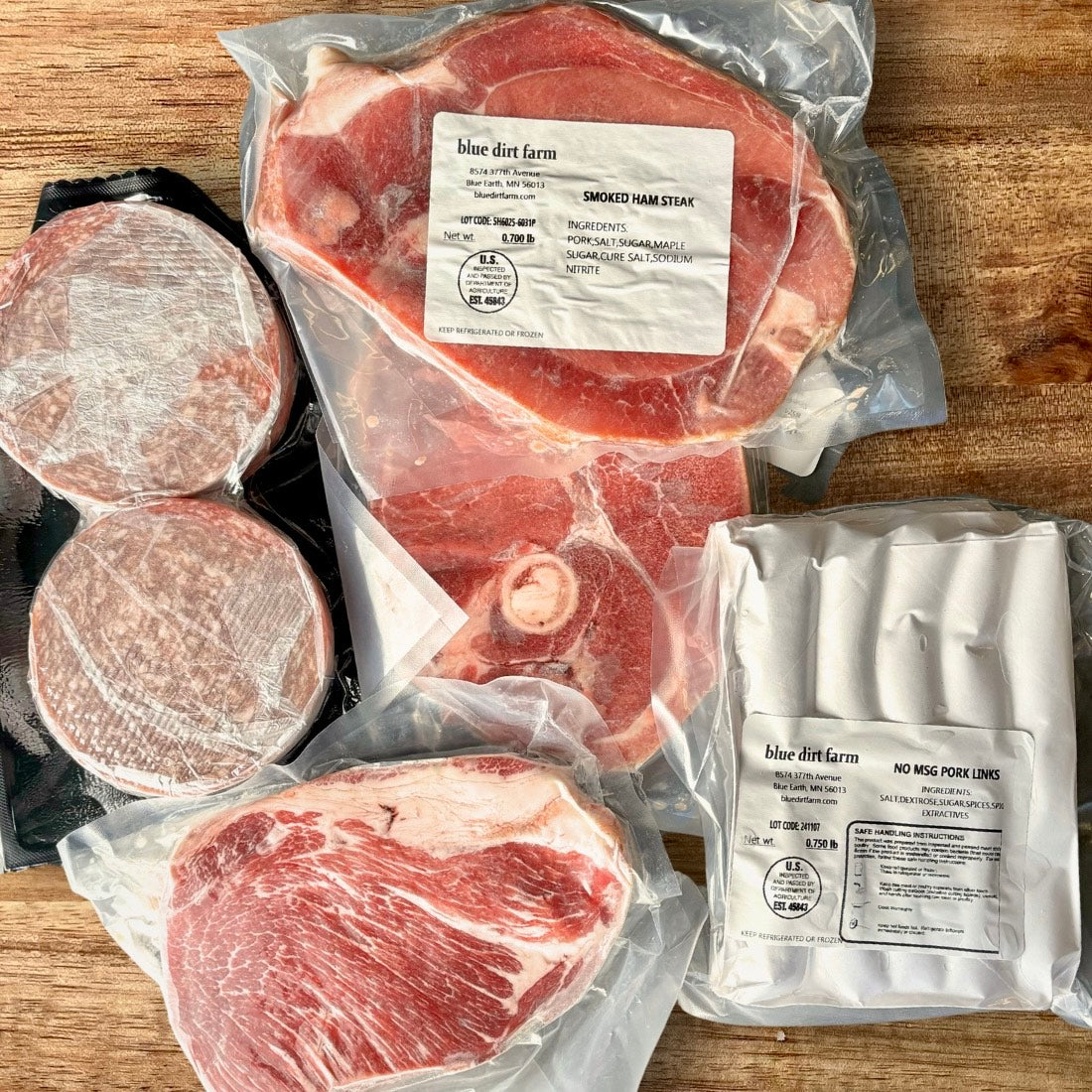 Contents of the Awaken Box featuring Cottage Bacon, Smoked Ham Steaks, and Italian Pork Sausage Patties arranged on a cutting board.