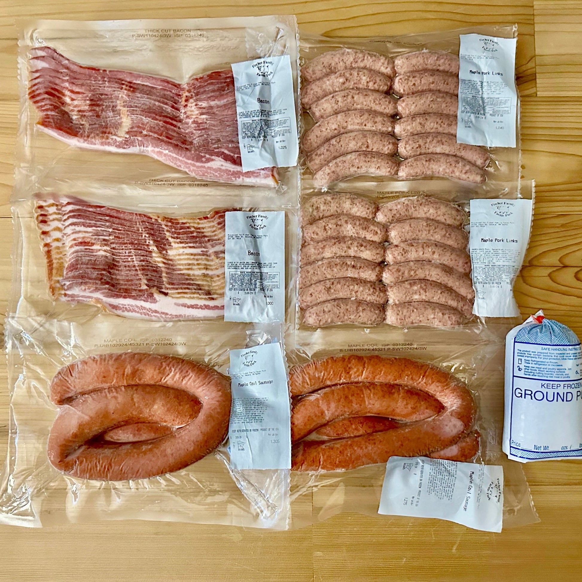 Contents of the Breakfast Box from Fischer Family Farms arrayed on a table. Consists of 2 packs bacon, 2 packs pork breakfast sausage links, 2 pork coil sausages, and 1 package ground pork sausage.