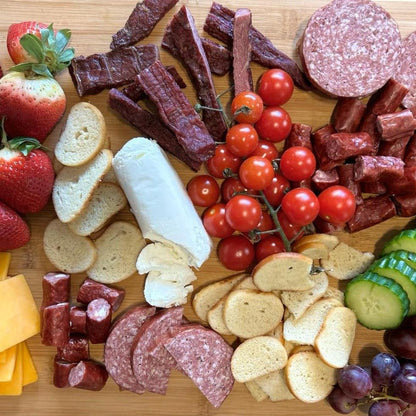 A charcuterie selection arranged on a cutting board that displays Verlinde Farms' American Wagyu summer sausage, steak strips, beef sticks, and other accoutrements.