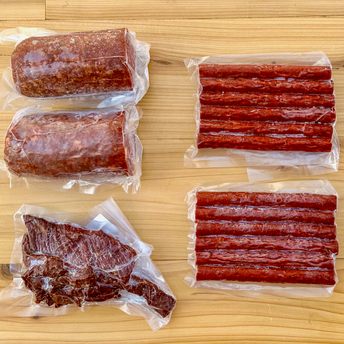 Two summer sausages, two packs of beef sticks, and a package of beef jerky strips from Verlinde Farms, making up the contents of the American Wagyu Charcuterie Box.