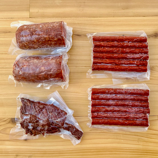 Two summer sausages, two packs of beef sticks, and a package of beef jerky strips from Verlinde Farms, making up the contents of the American Wagyu Charcuterie Box.